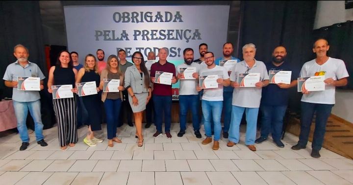 Participantes com os certificados diante do slide de agradecimento pela presença