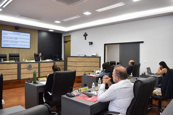 Servidores nas bancadas do plenário durante o curso, com o material projetado