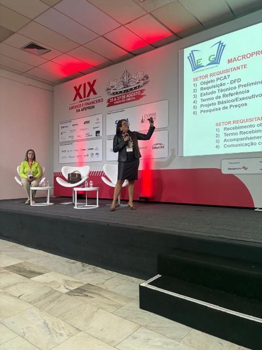 Dra Gislany no palco de congresso apresentando o fluxo do setor requisitante no telão