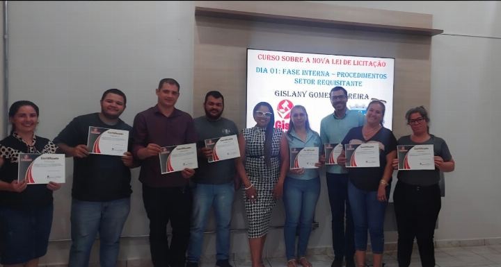 Turma com os certificados diante do slide do curso sobre a nova Lei de Licitações