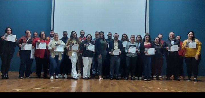 Turma numerosa com os certificados no palco de auditório