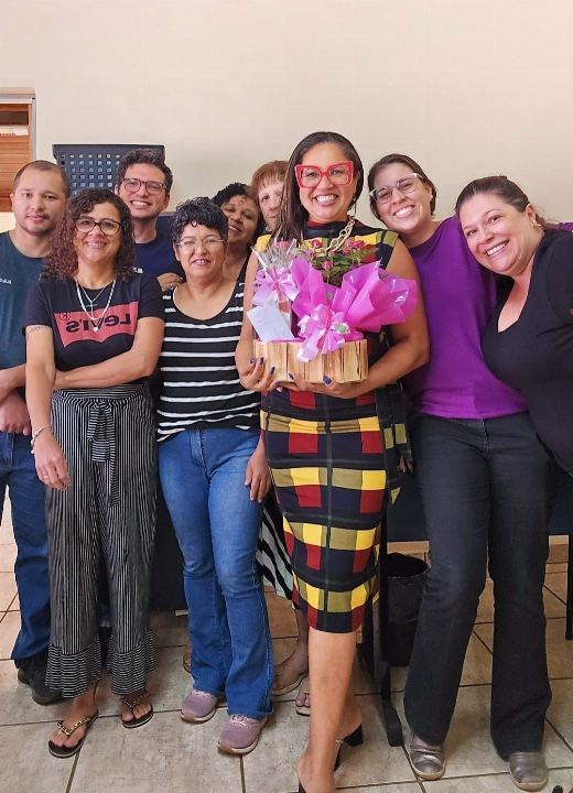 Dra Gislany com um buquê ao lado da equipe ao fim do treinamento
