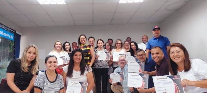 Participantes com os certificados em sala clara ao fim do treinamento