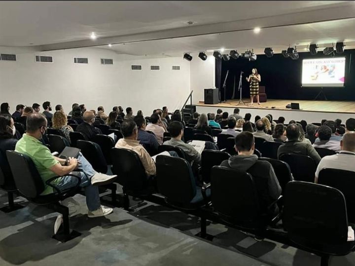 Auditório cheio durante a palestra, visto do fundo da plateia