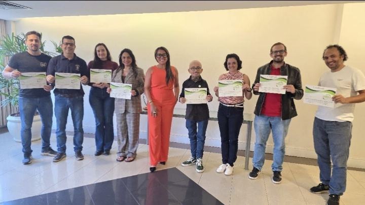Participantes com os certificados em sala ampla ao fim do curso