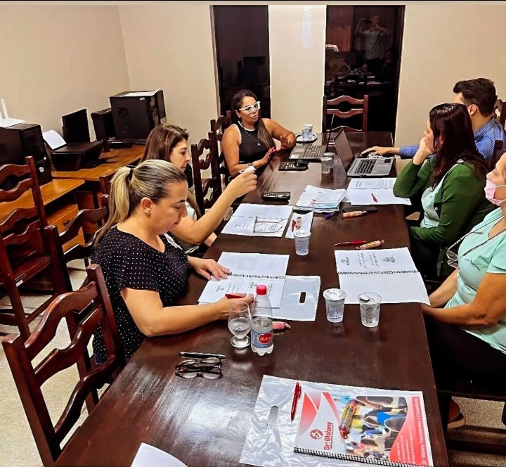 Equipe trabalhando com documentos e computadores em mesa de reunião durante consultoria