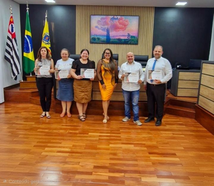 Participantes com os certificados diante das bandeiras oficiais, em plenário de piso de madeira