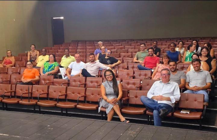 Turma reunida no auditório de poltronas vermelhas ao fim do curso