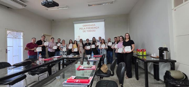 Turma predominantemente feminina exibindo os certificados em sala de aula