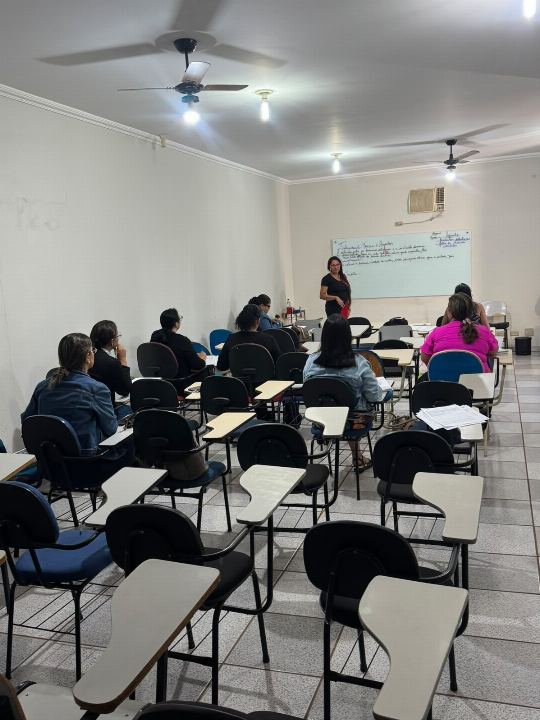 Dra Gislany em pé junto ao quadro branco explicando o conteúdo para a turma do preparatório para concursos